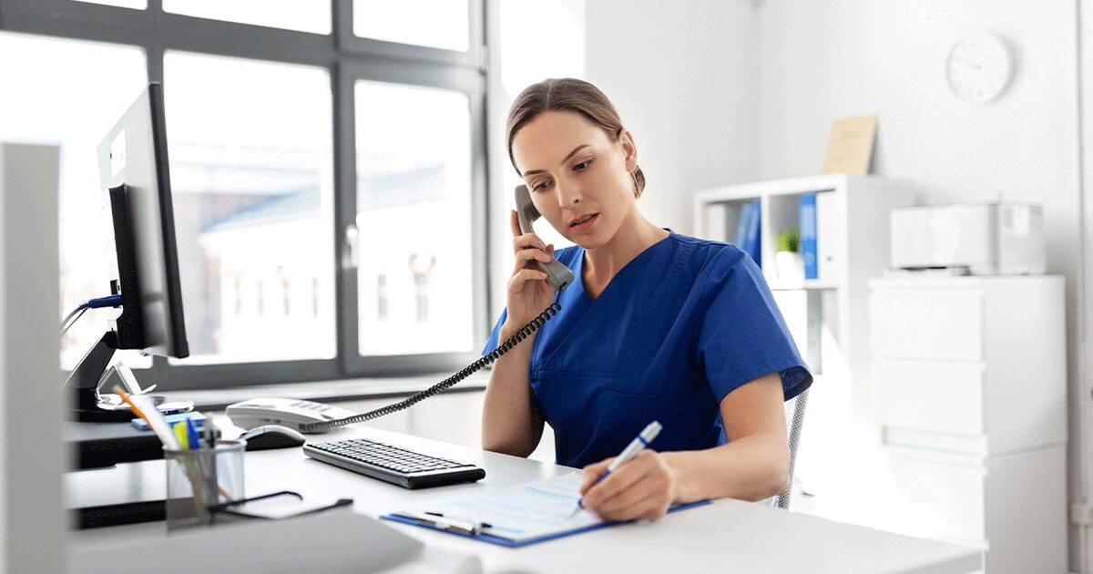 A medical professional giving advice to a patient over the phone while taking notes during a pregnancy consultation.